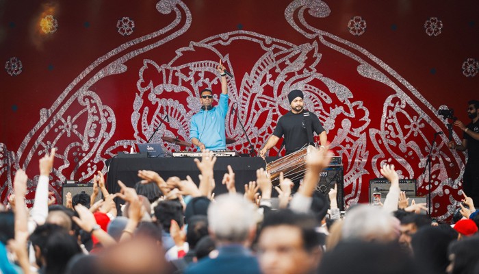 Musicians in the background acknowledge a busy crowd of festivalgoers