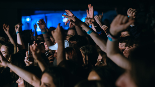 A crowd in a darkened venues, arms raised in celebration